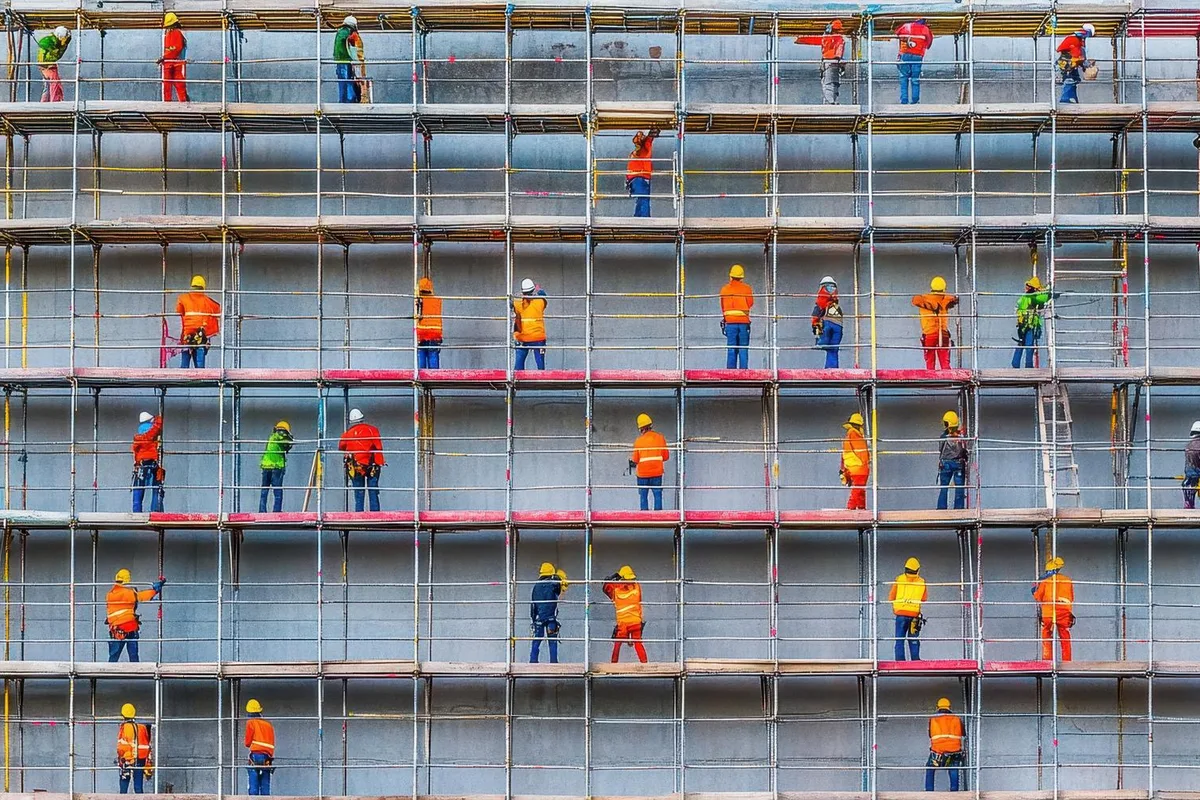 Trabajadores montando un andamio con equipo de protección para trabajo en alturas