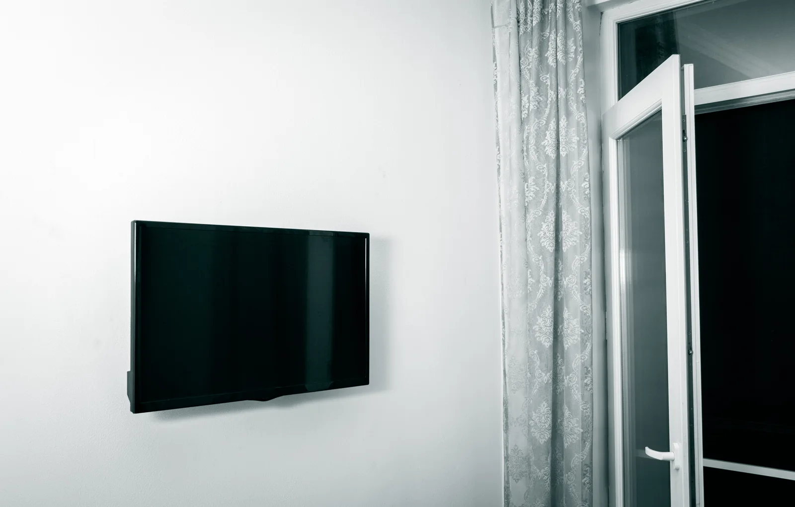 Televisor plano montado en la pared con un soporte fijo de perfil bajo